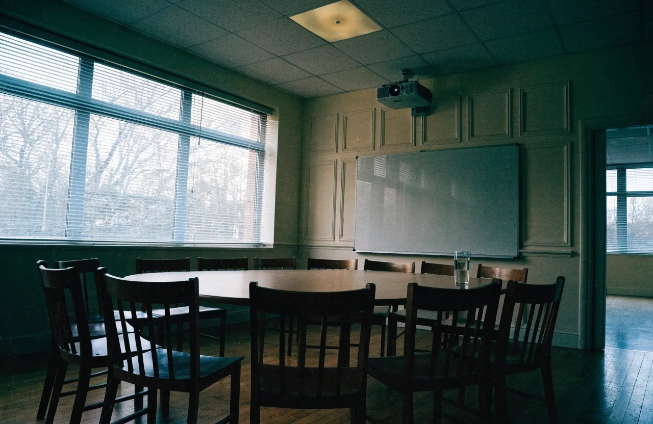 Empty London classroom in daylight with chairs turned toward a blank whiteboard and a projector glow on the wall